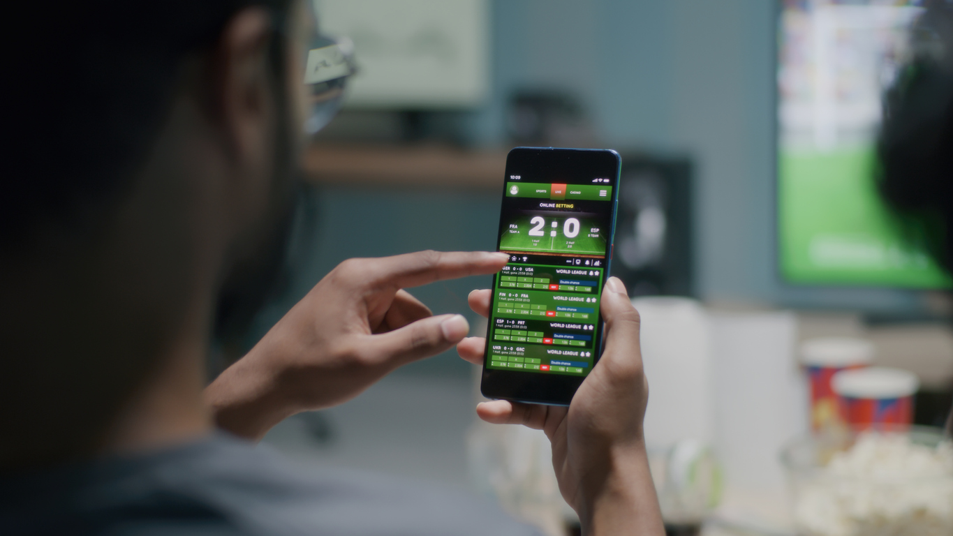 Unrecognizable fans with smartphones discussing online stakes and watching football competition on TV at home. We compared the betting prices at some of the best Pennsylvania sportsbooks. Here are the ones that offer the best odds and highest returns on y